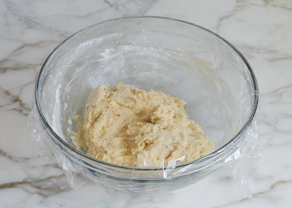 Dough in a plastic-wrap-covered bowl.