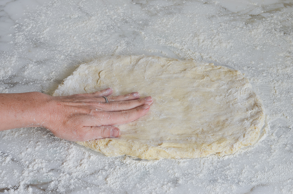 Person pressing dough into a rectangle.