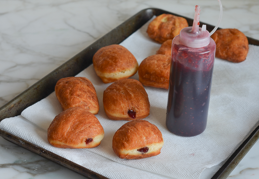 Squeeze bottle of jam with filled donuts.