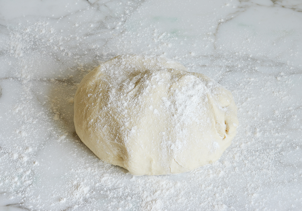 Ball of kneaded dough  on a floured countertop.
