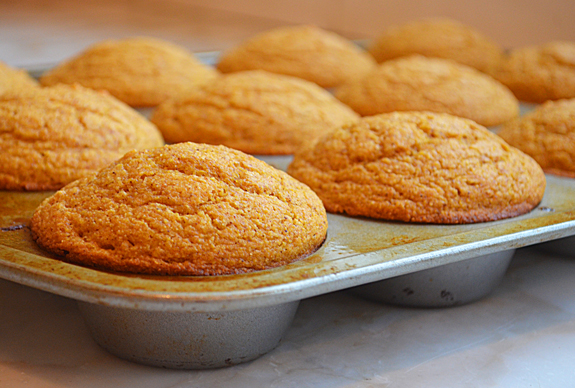 Pumpkin cornbread muffins in a muffin pan.
