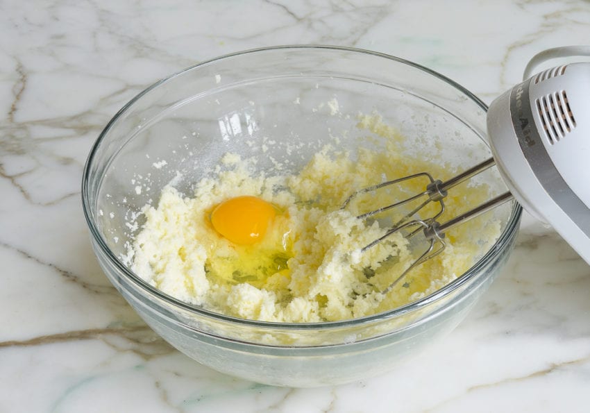 Egg in a bowl of creamed butter and sugar.