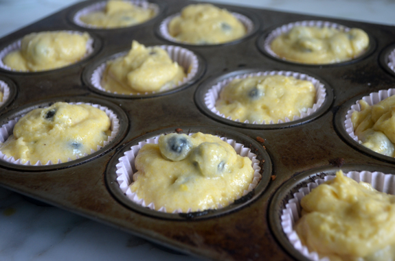 Muffin pan filled with blueberry cornbread muffin batter.