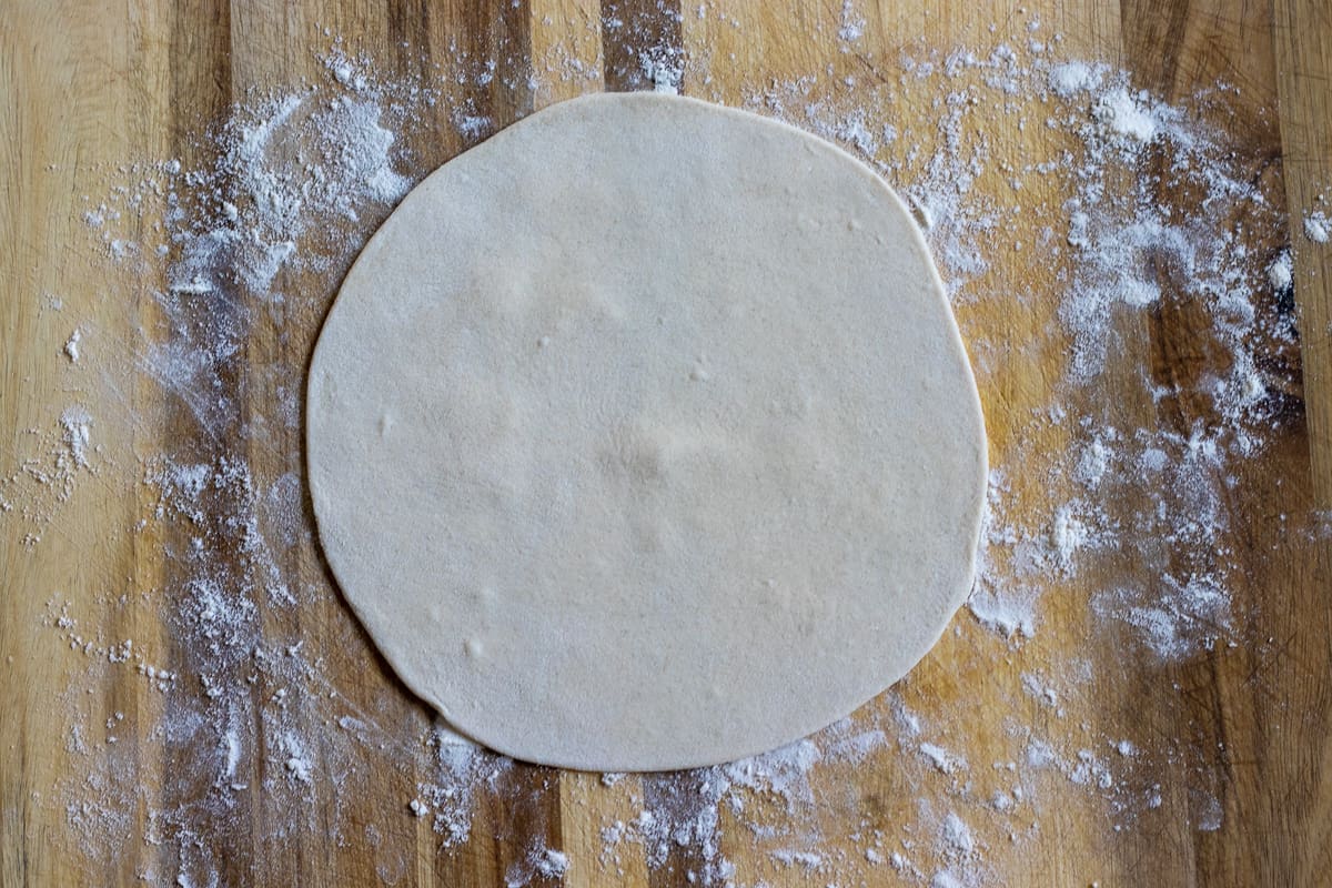 The dough ball is rolled out into a circle
