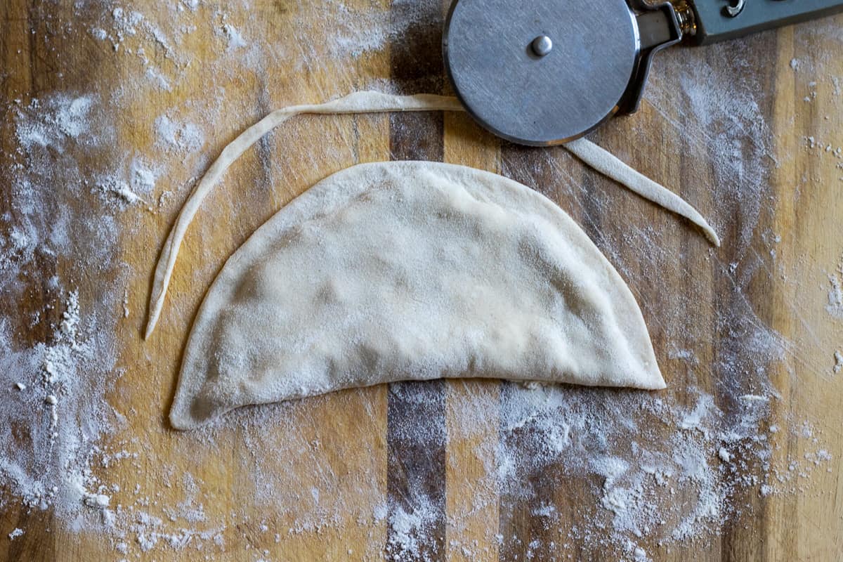 the seams of Chebureki is pinched to seal and the sides are trimmed 