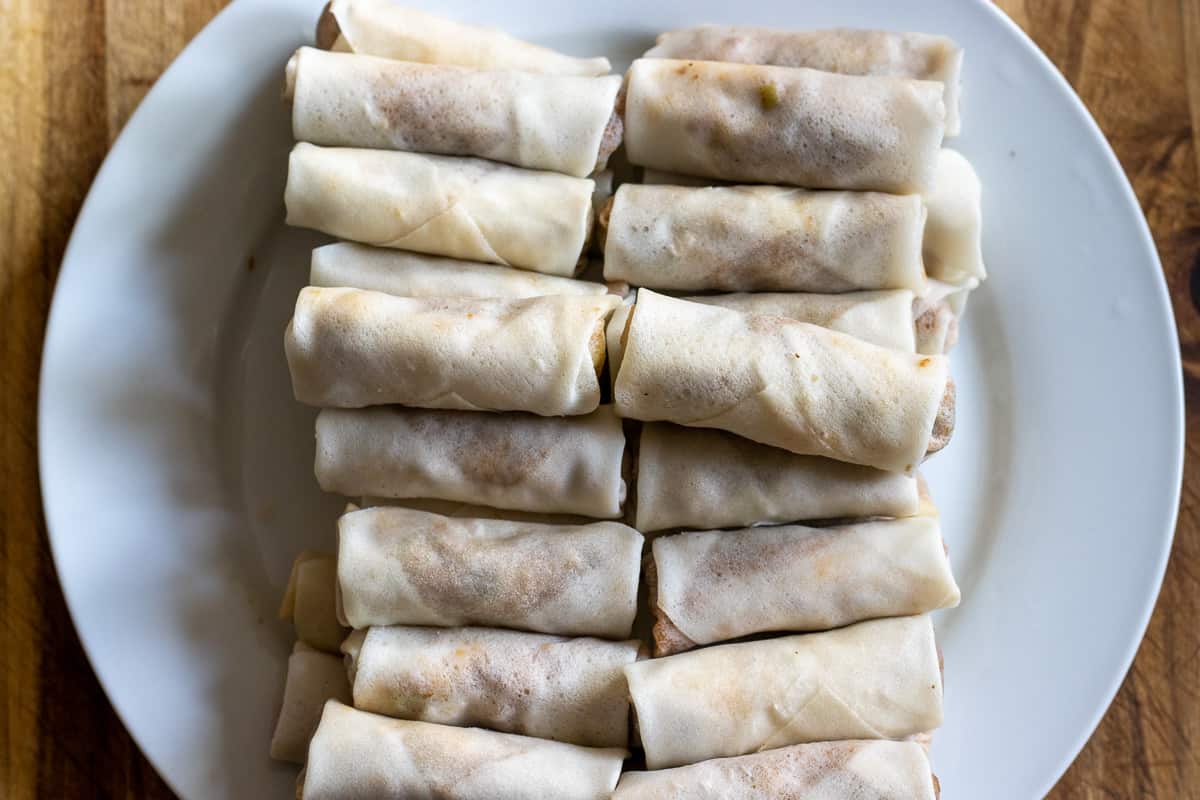 Duck spring rolls are on a plate before frying
