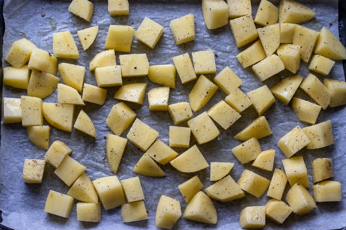potato cubes are drizzled with oil, and seasoned with salt and pepper