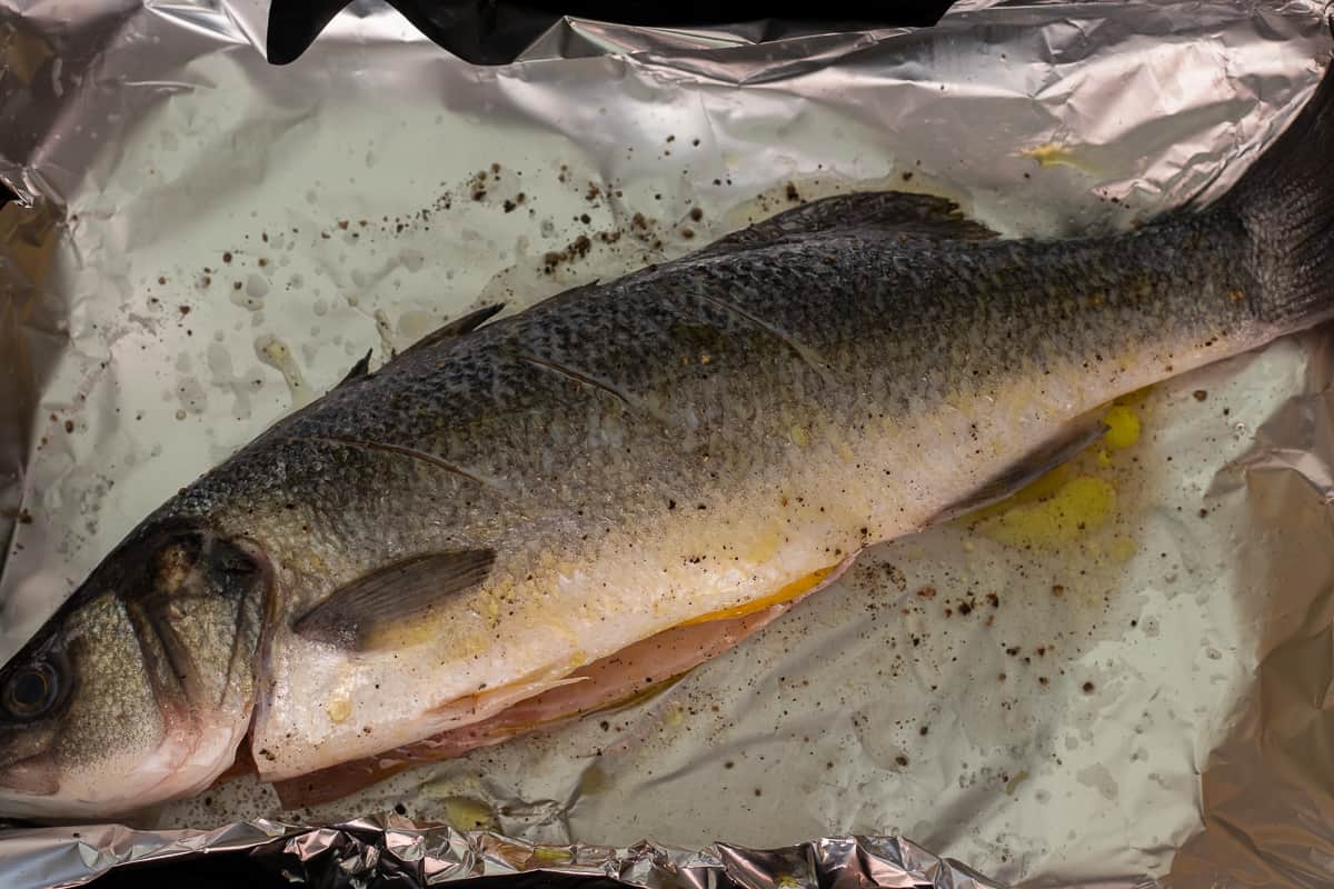 a whole sea bass is seasoned and rubbed with olive oil