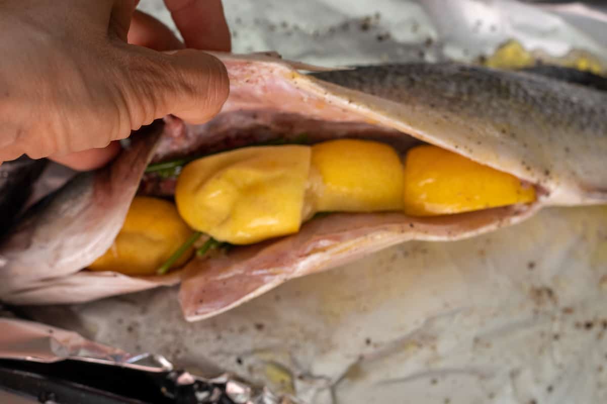 sea bass is stuffed with lemon, parsley stalks and garlic