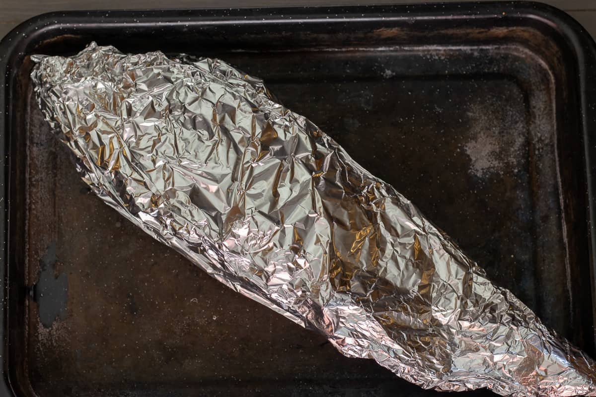sea bass is wrapped in foil and placed on a tray