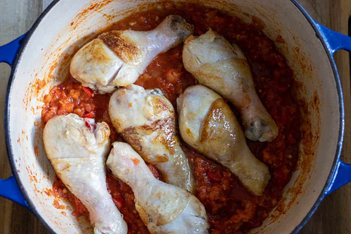 Chicken legs are returned to the pan with the tomato sauce