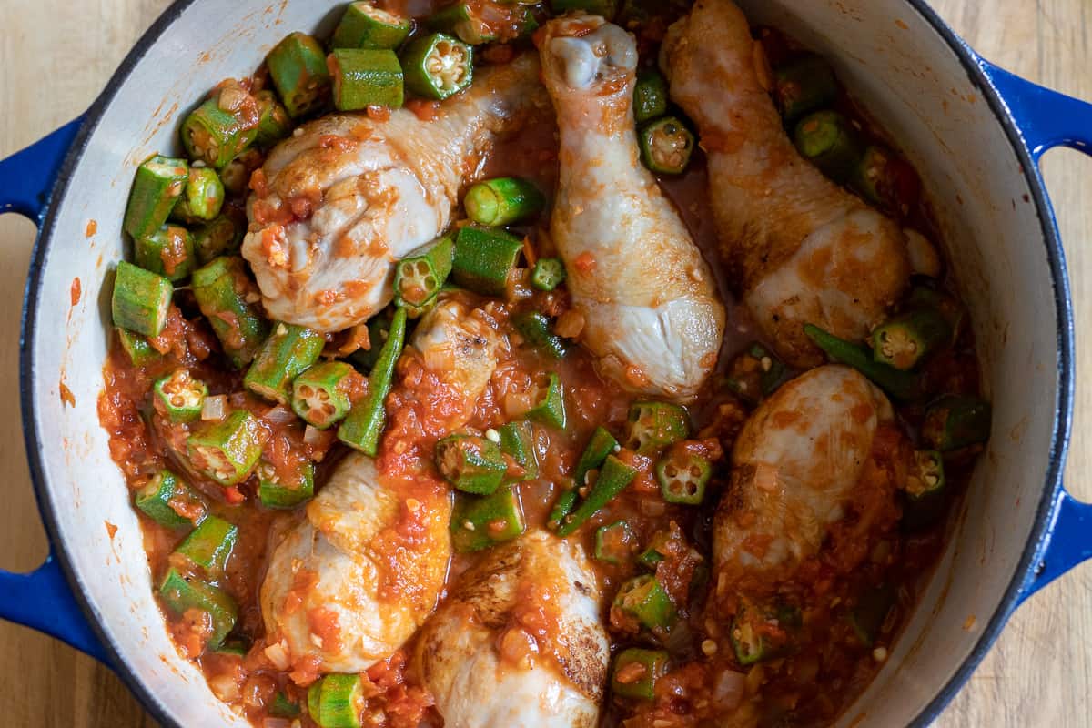 Okra, stock, and seasoning are added to the pan