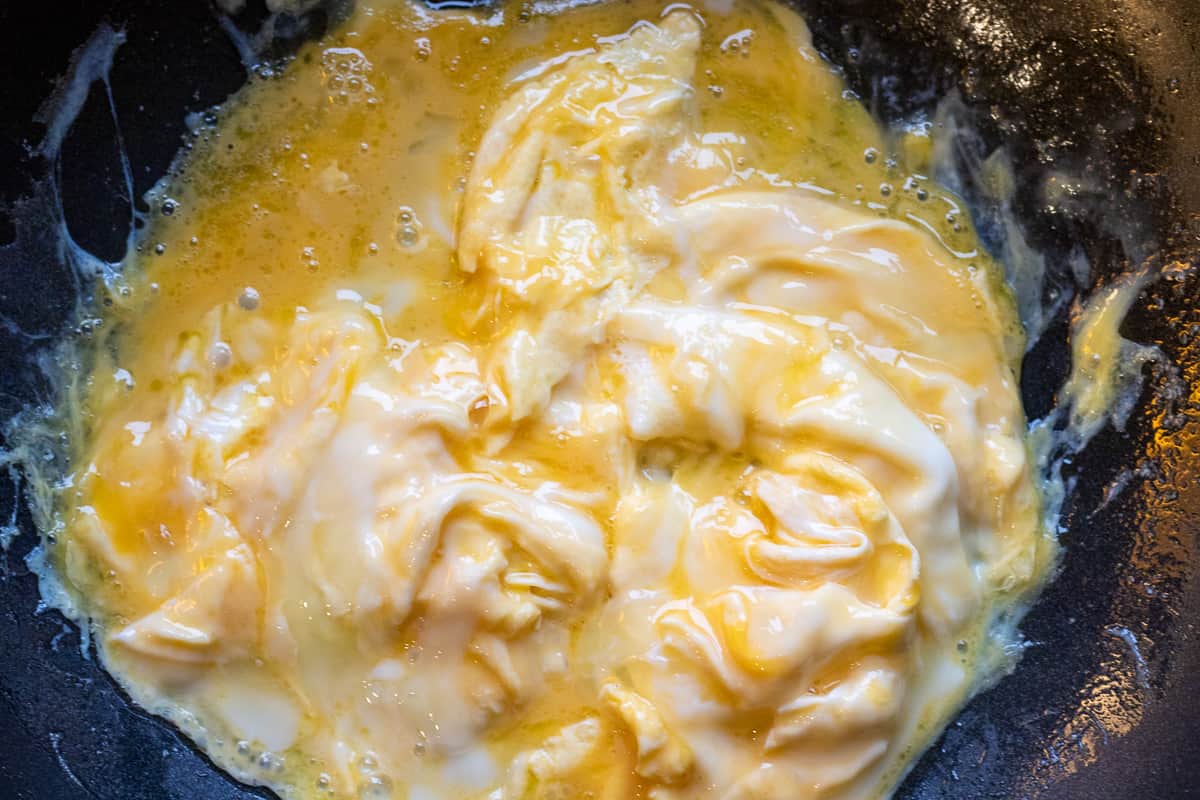 cooking the eggs in a wok with melted butter