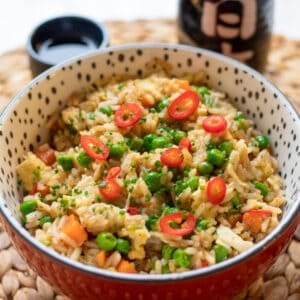spicy egg fried rice garnished with chillies and chives