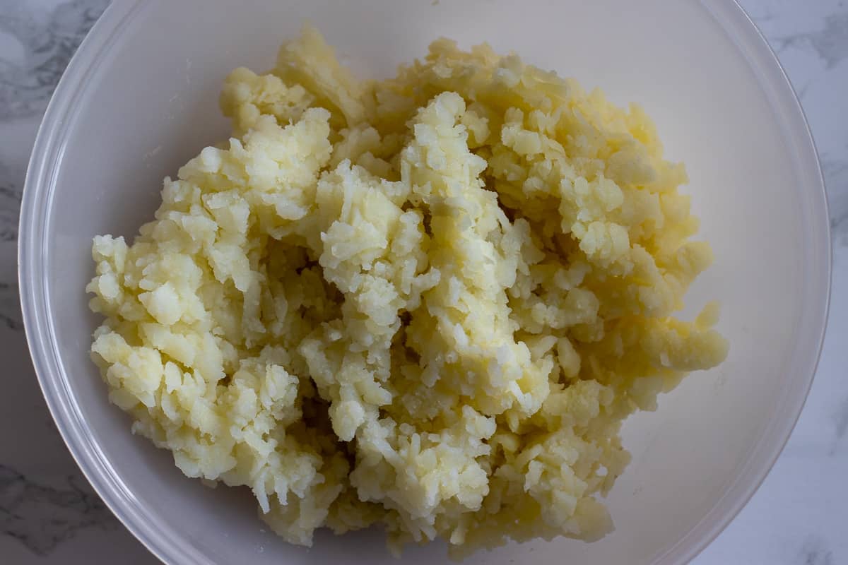 boiled potatoes are grated in a bowl