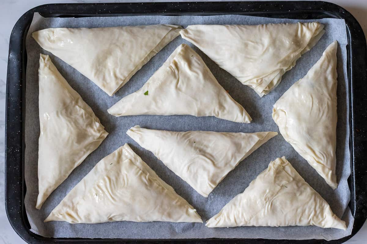 Cheese boreks are placed on a baking sheet