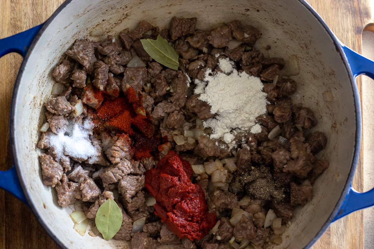 tomato paste, flour and spices are added to the beef