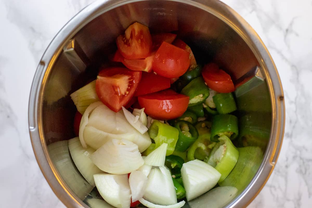 the peppers, tomatoes and onions in a bowl of a food processor