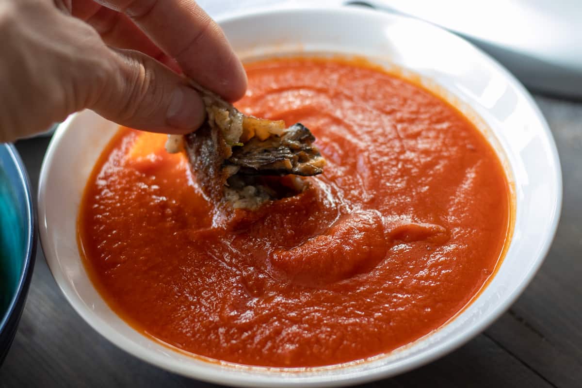 dipping half of a rice ball in a tomato sauce