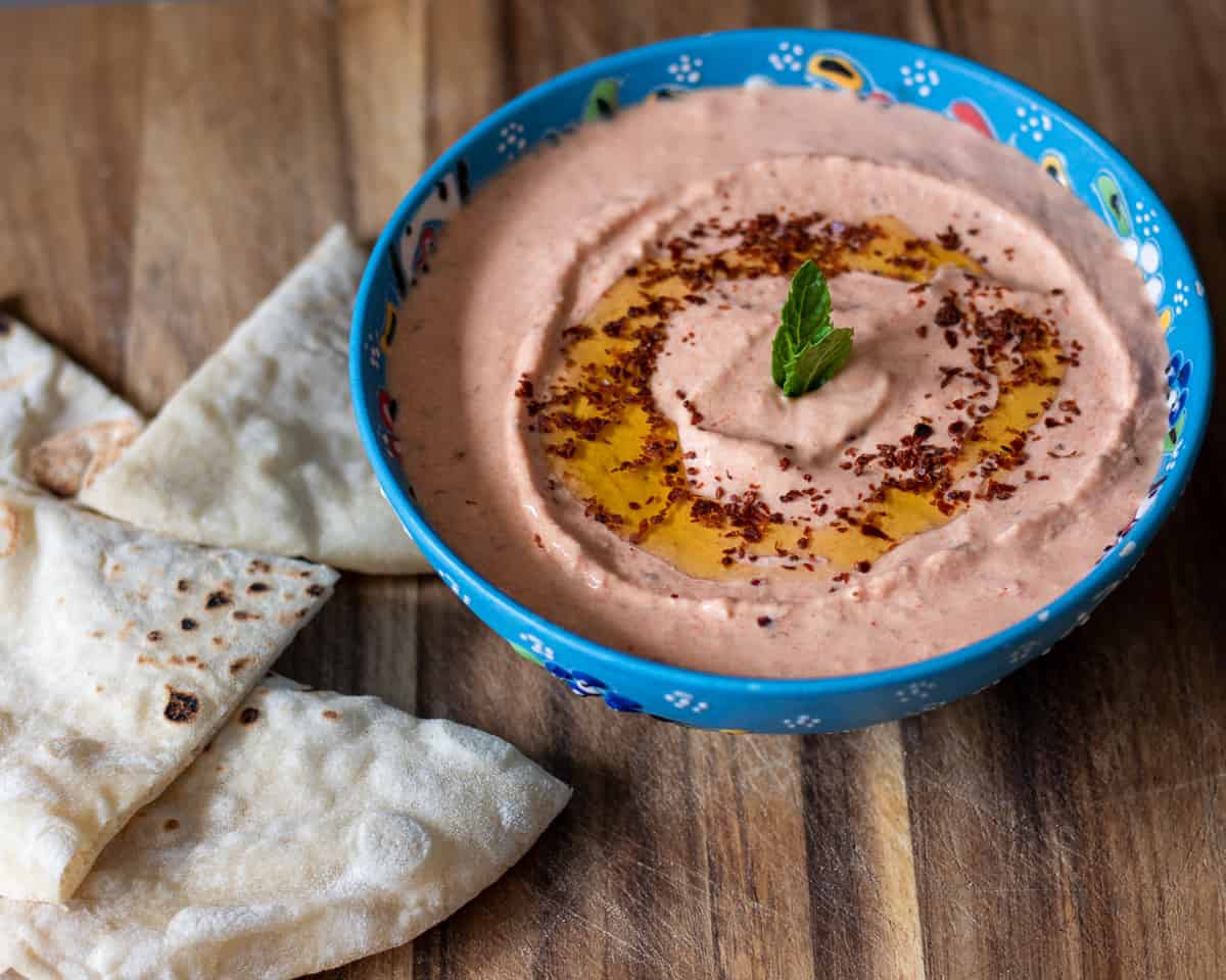 feta dip served in a bowl with drizzled olive oil and pita bread wedges