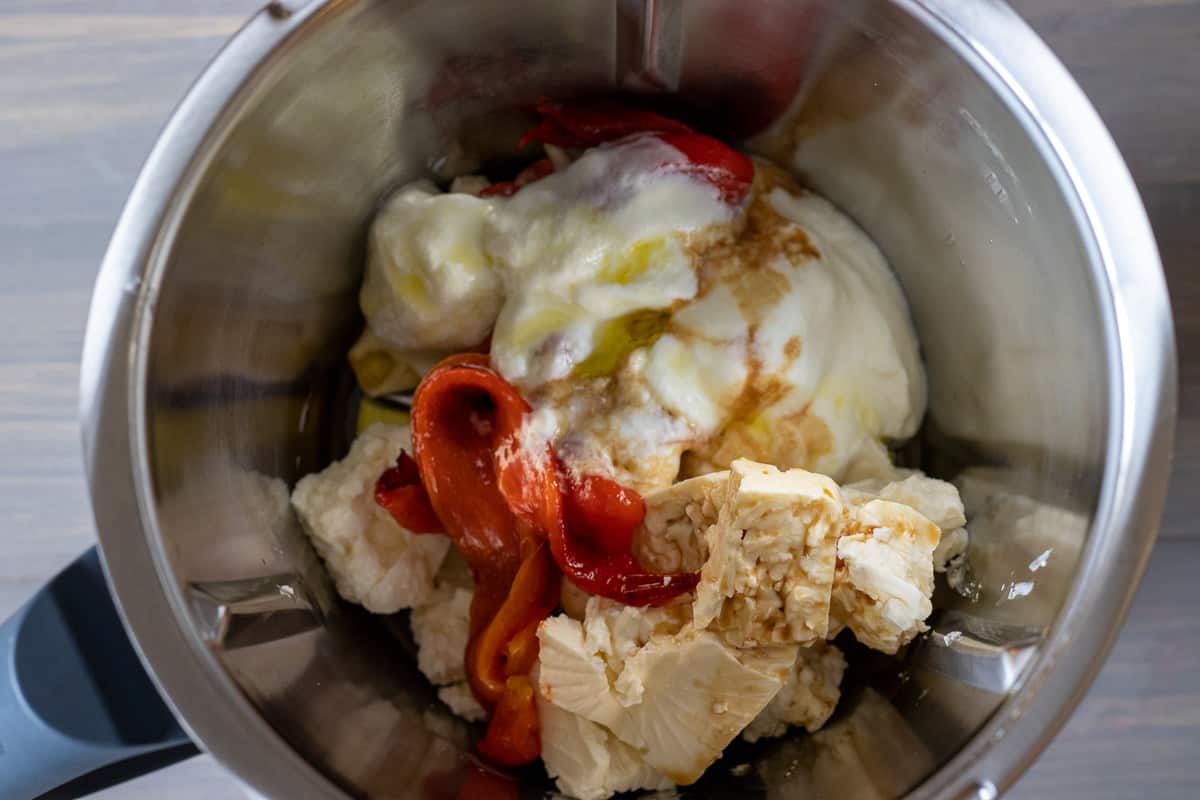 Feta, yoghurt, garlic and red pepper in a bowl of a food processor.