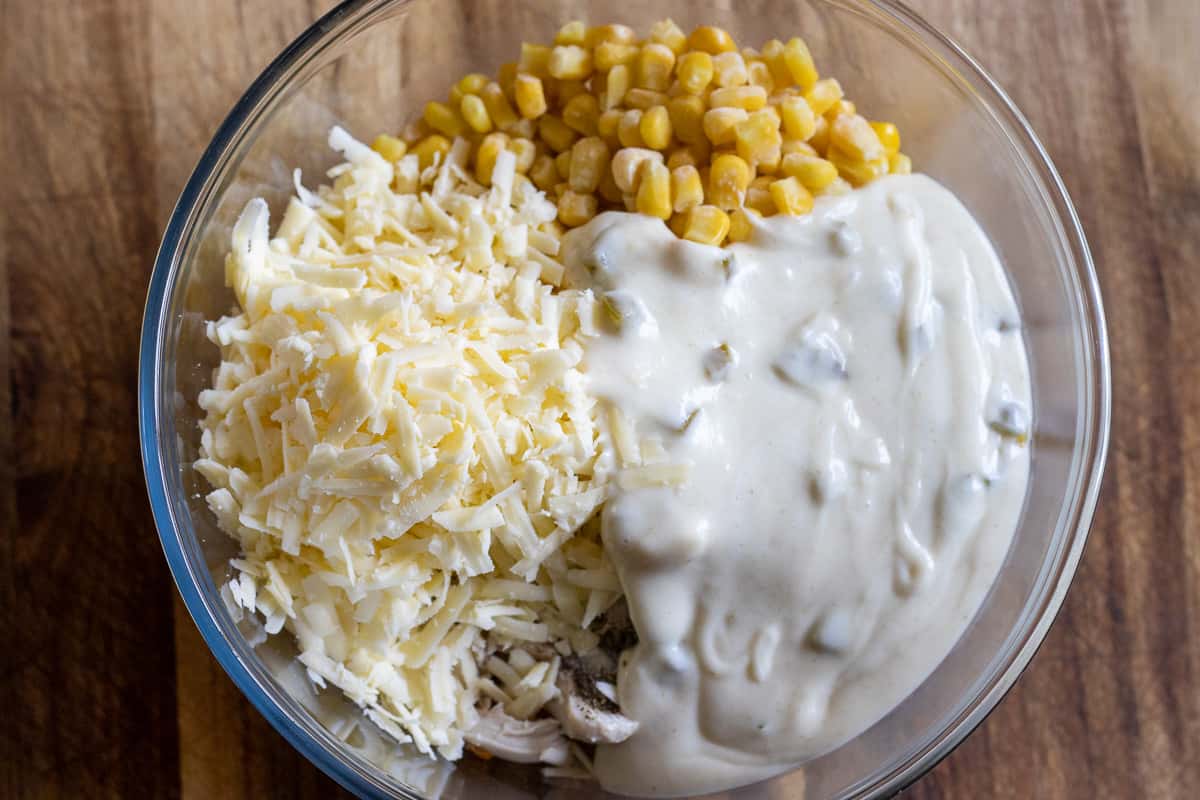 shredded chicken is mixed with sweetcorn, grated cheese, white sauce and green onions