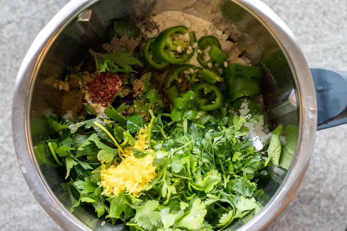 chickpeas, herbs, lemon zest and chillies are placed in a bowl of a food processor 