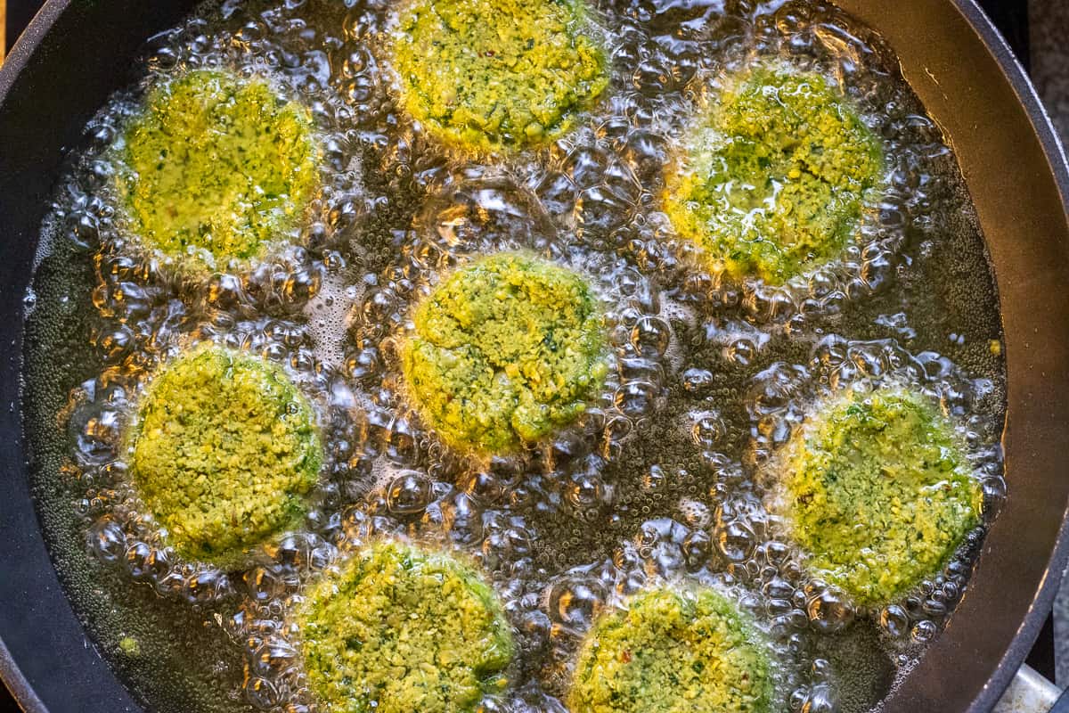 8 pieces of falafel patties are frying in hot oil