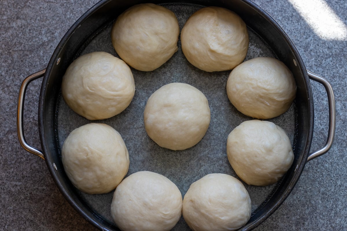 nine dough balls are placed in a cake tin