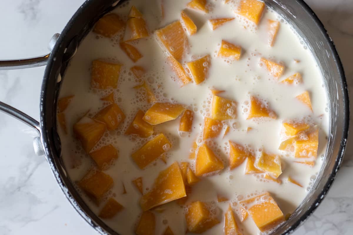 chopped pumpkin is placed in a pan with stock and cream