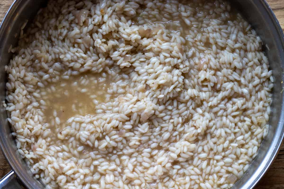 adding stock to risotto until the rice is cooked to al dente