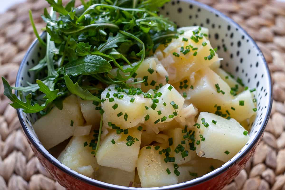 potato salad is garnished with chives and serve with rocket leaves