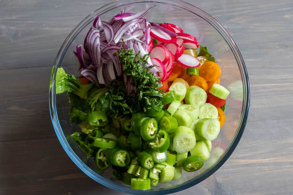 Vegetables for fattoush salad placed in a large glass bowl