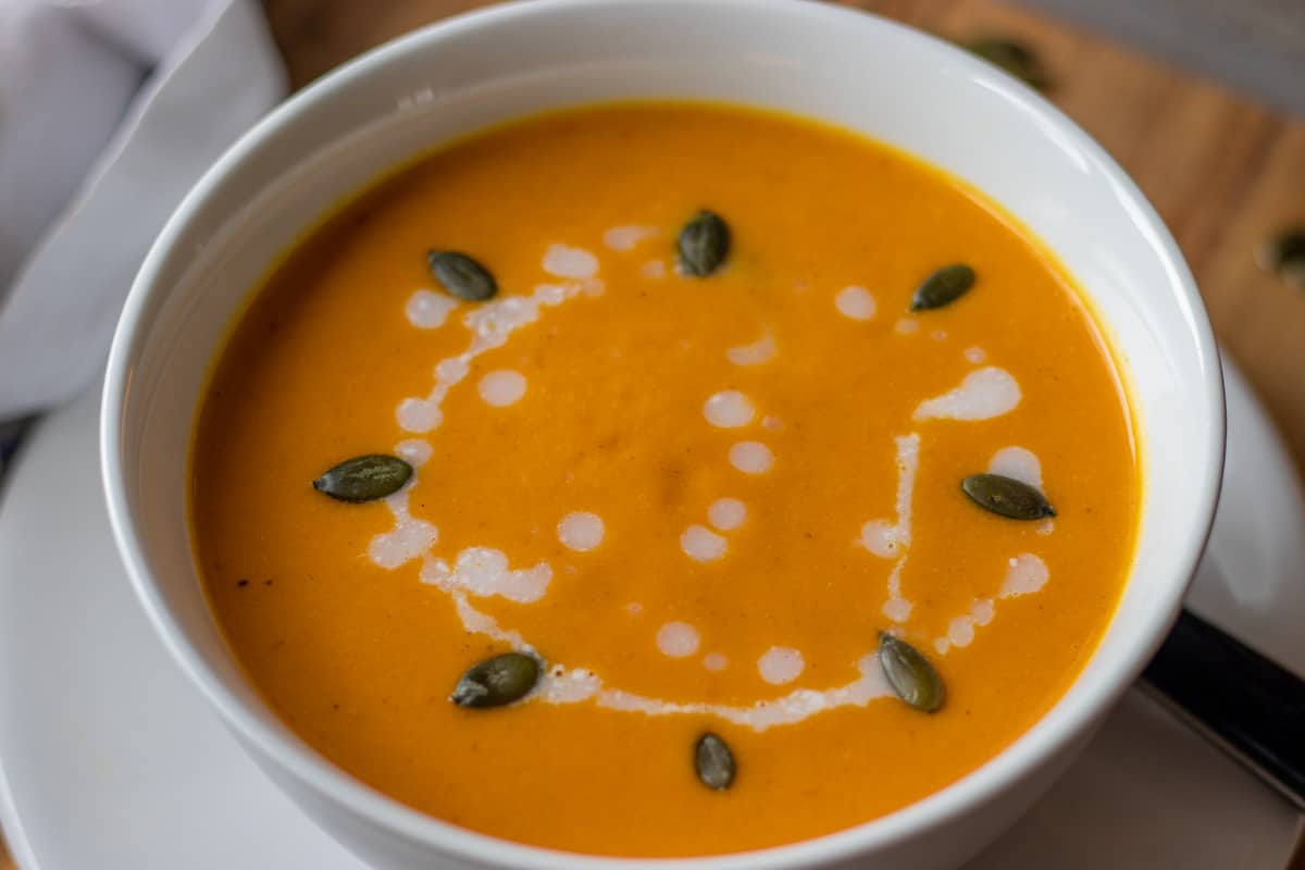 spiced butternut squash soup served in a bowl garnished with coconut milk