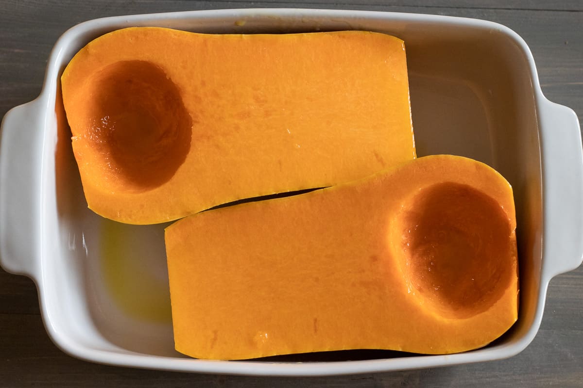 butternut squash is cut in halves and the seeds are scooped out