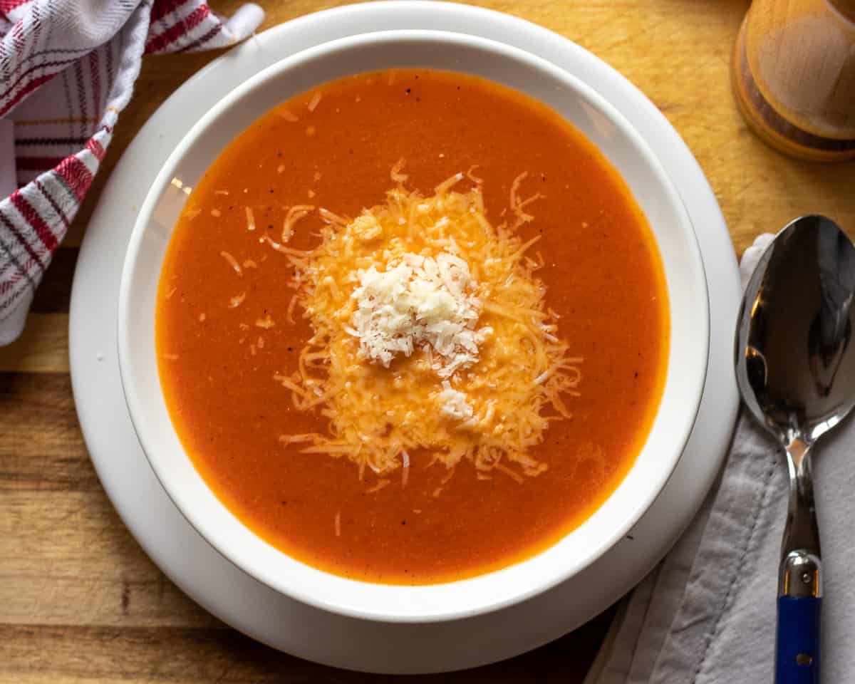 roasted red peppers and tomato soup in a bowl garnished with parmesan