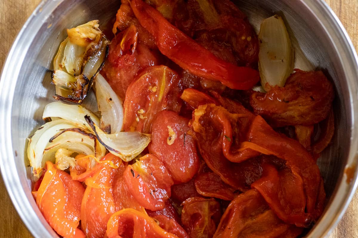 red peppers, tomatoes, onions and garlic are placed in a pan for tomato soup