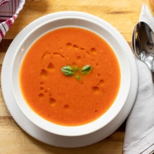tomato soup served in a bowl with basil leaves