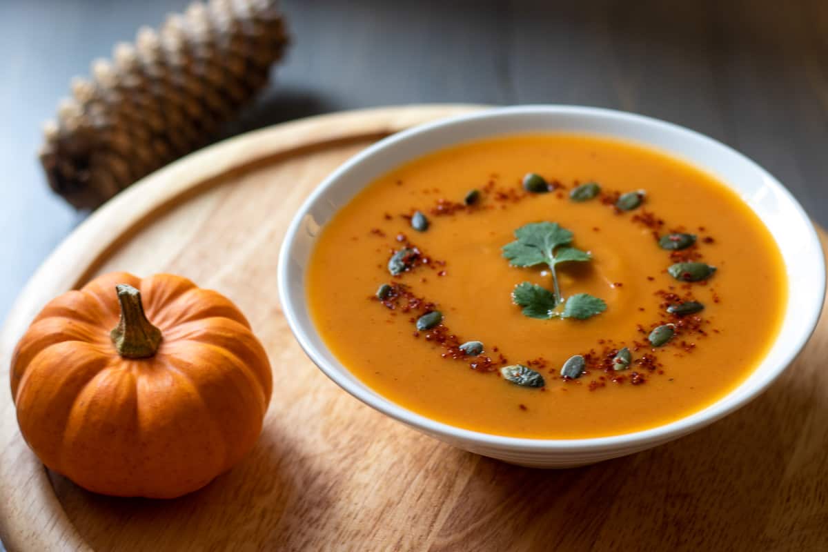 Pumpkin soup served in a bowl garnished with pumpkin seeds and chilli flakes