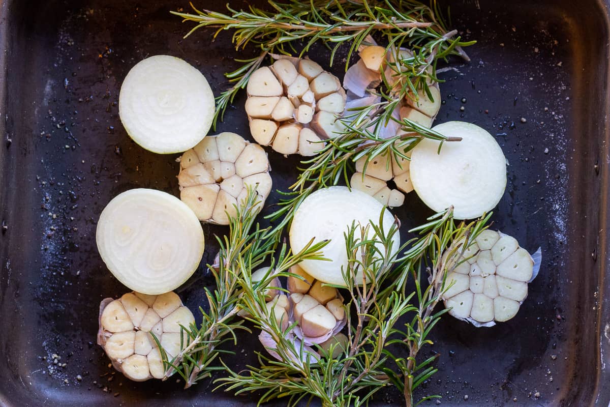onions, garlic and rosemary ate placed in a tray