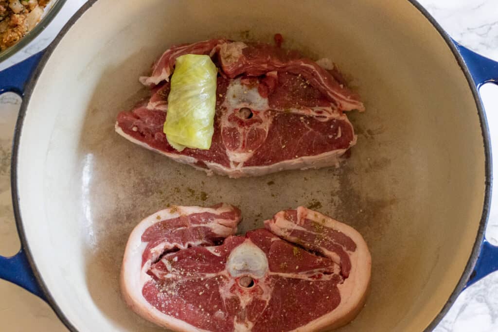 Lamb chops are placed to the bottom of a Dutch oven