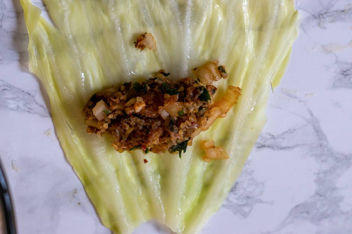 a spoonful of filling is placed on cabbage leaf