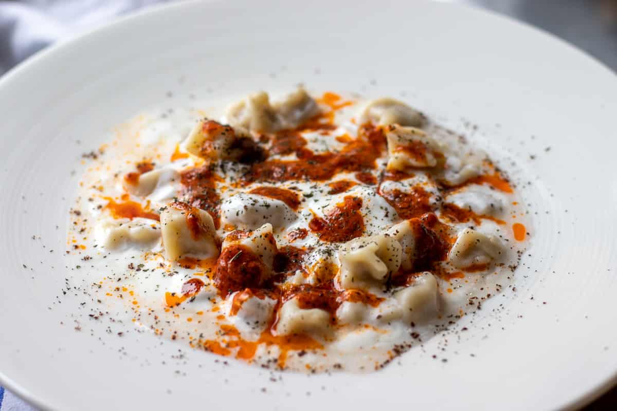 manti - Turkish ravioli is typically garnished with yogurt sauce and tomato sauce