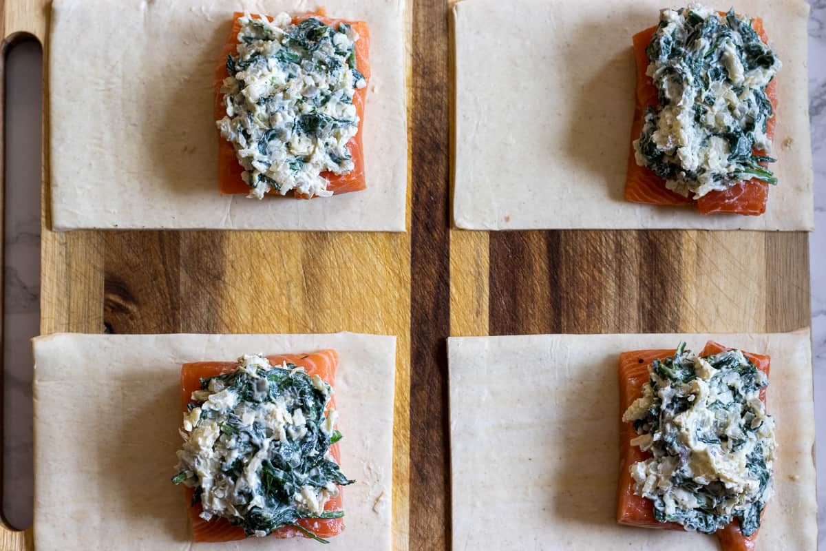 spinach filling is spooned out on salmon fillets