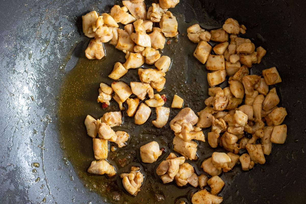 Sautéing the chicken pieces in a pan with butter.