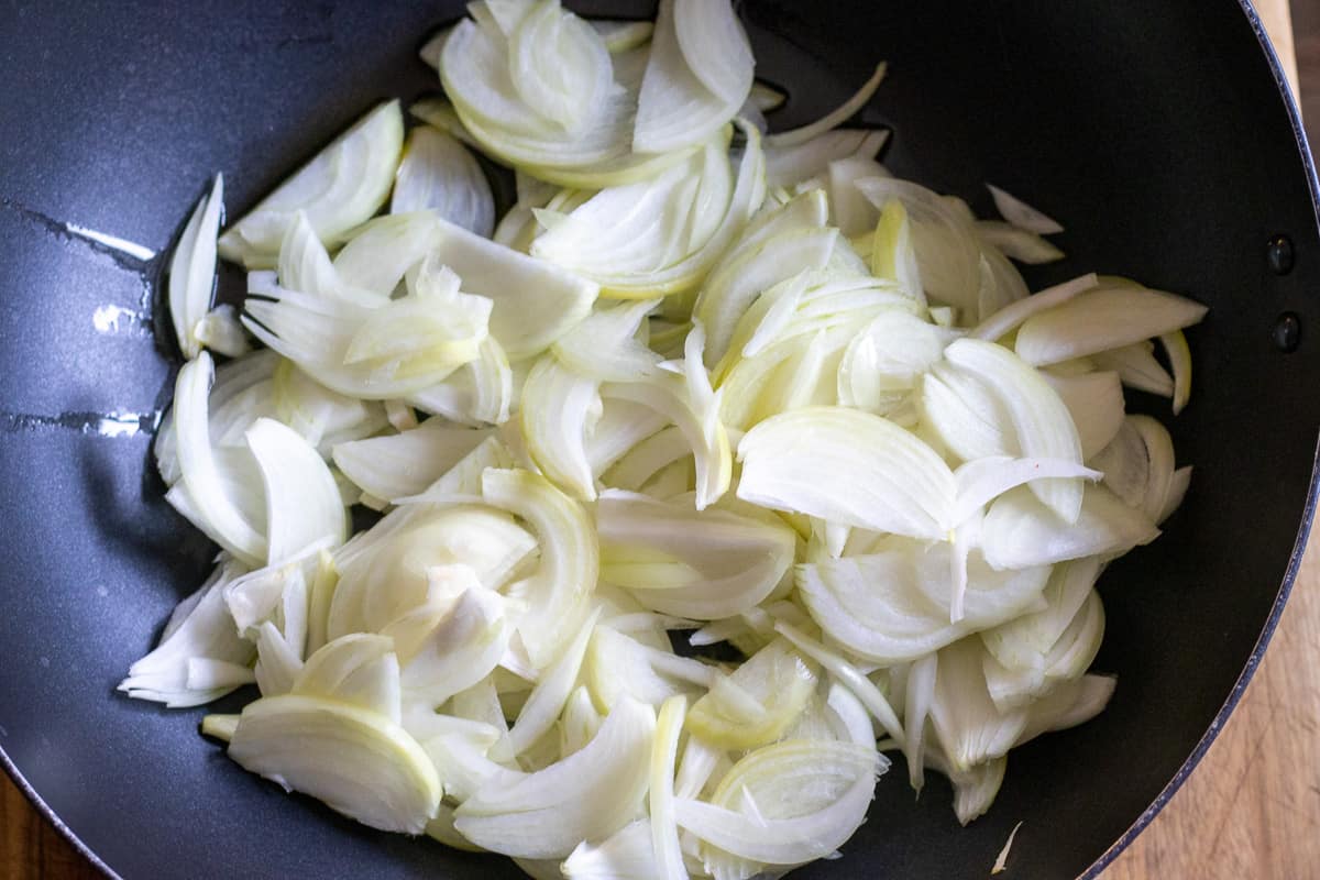sliced onions are placed in a wok