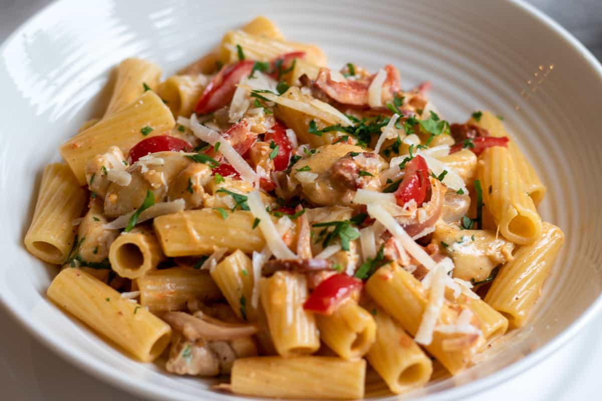 Chicken and chorizo pasta is garnished with parmesan and parsley before serving