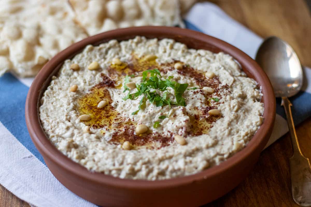 Mutabal (Roasted Eggplant Dip) is garnished with chopped parsley, sumac and olive oil