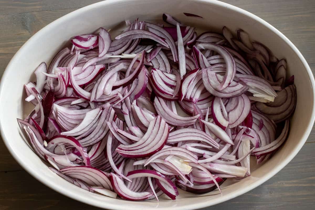 sliced red onions are placed in a baking dish