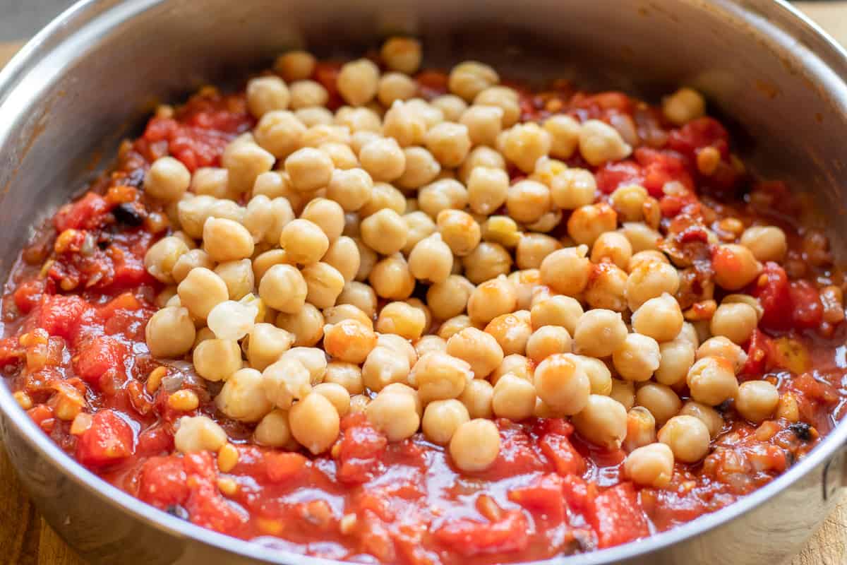 Chickpeas and chopped tomatoes added to the pan with sautéed onions.